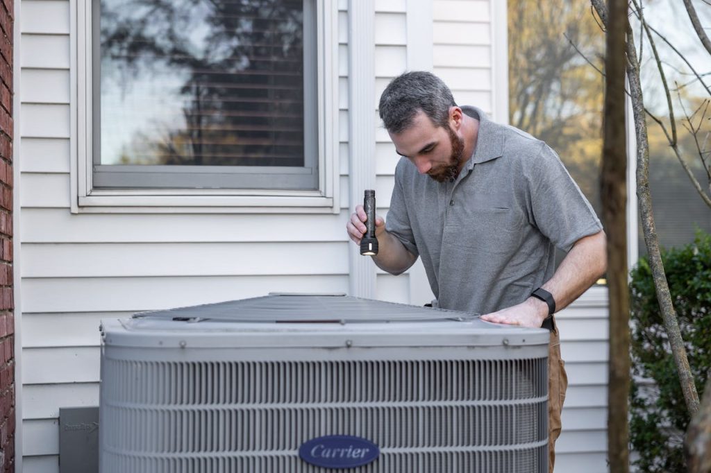 technician-inspecting-outdoor-hvac-unit-32497161 A technician inspects an outdoor HVAC unit for maintenance.